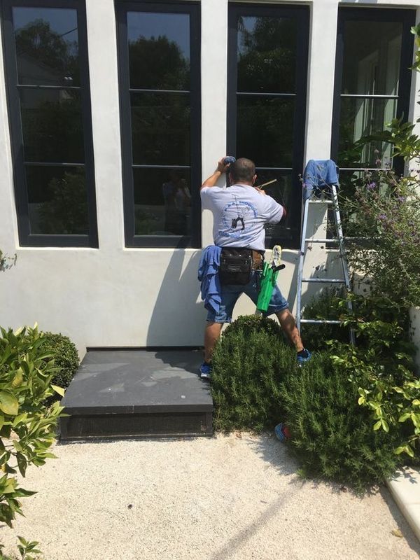 A man is standing on a ladder cleaning a window.