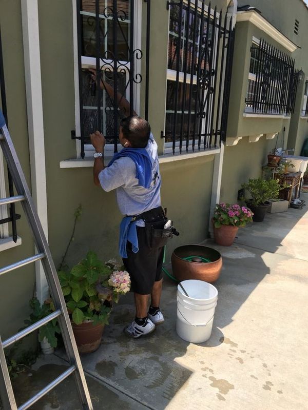 A man is standing on a ladder cleaning a window.