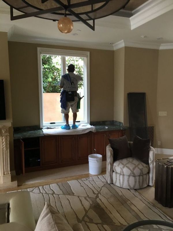 A man is cleaning a window in a living room