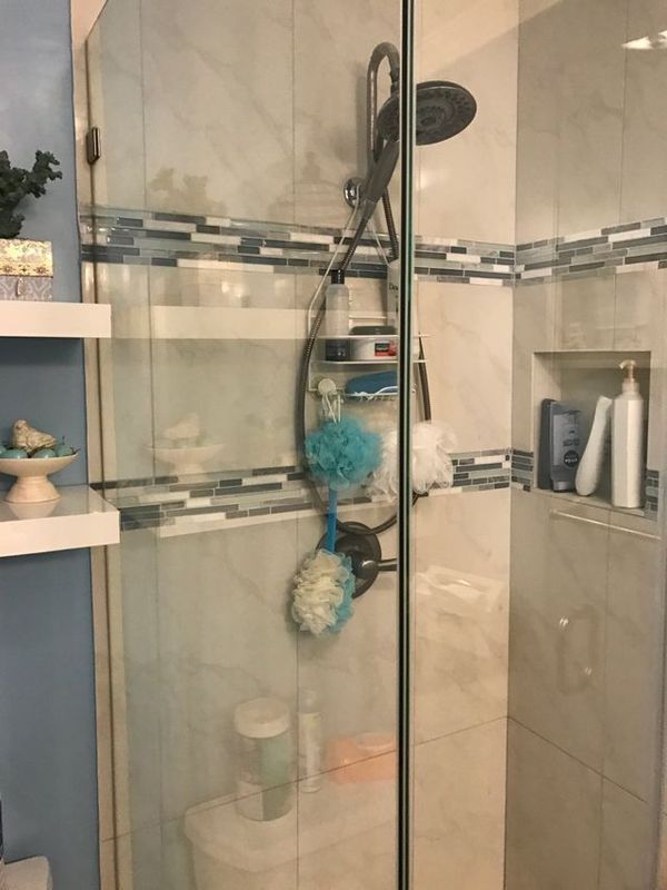 A bathroom with a shower , toilet , shelves and a shower head.