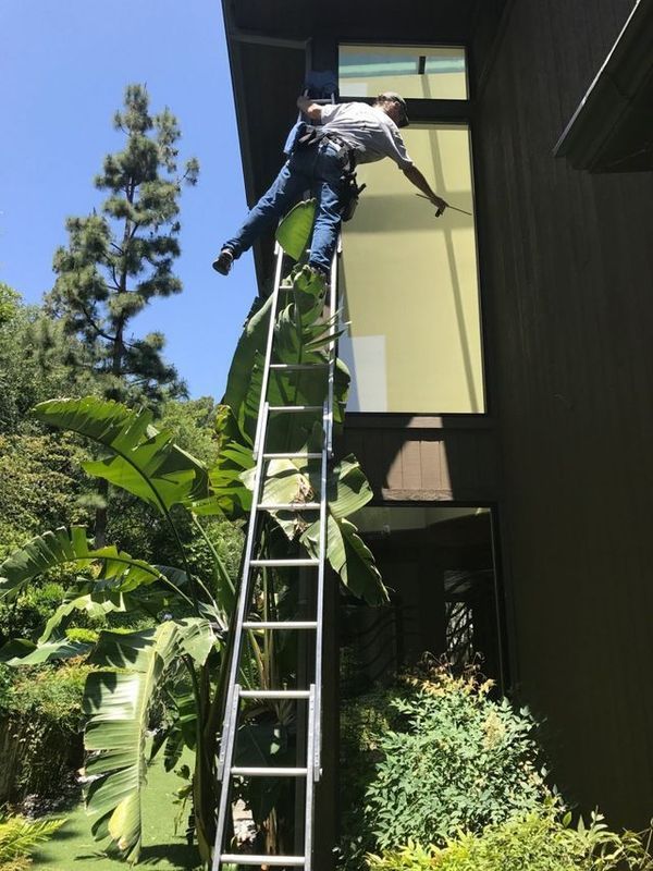 A man is standing on a ladder on the side of a building