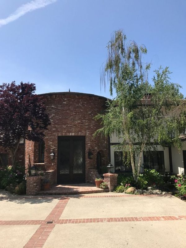 A large brick house with a driveway and trees in front of it