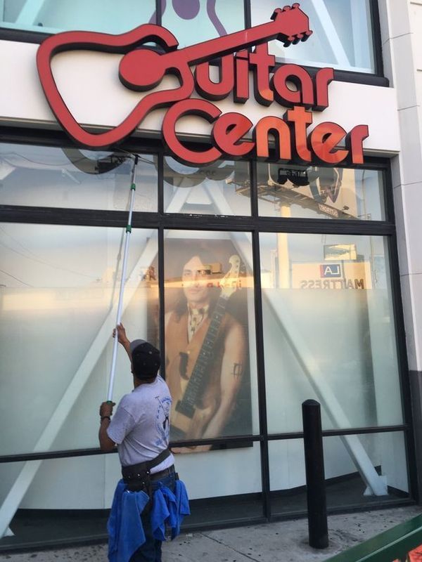 A man is cleaning the windows of the guitar center