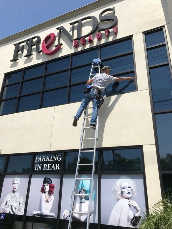 A man on a ladder is cleaning the windows of a building.