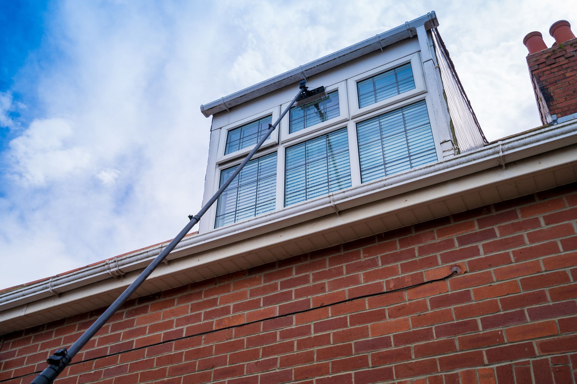 A window cleaner is cleaning a window on the roof of a brick building