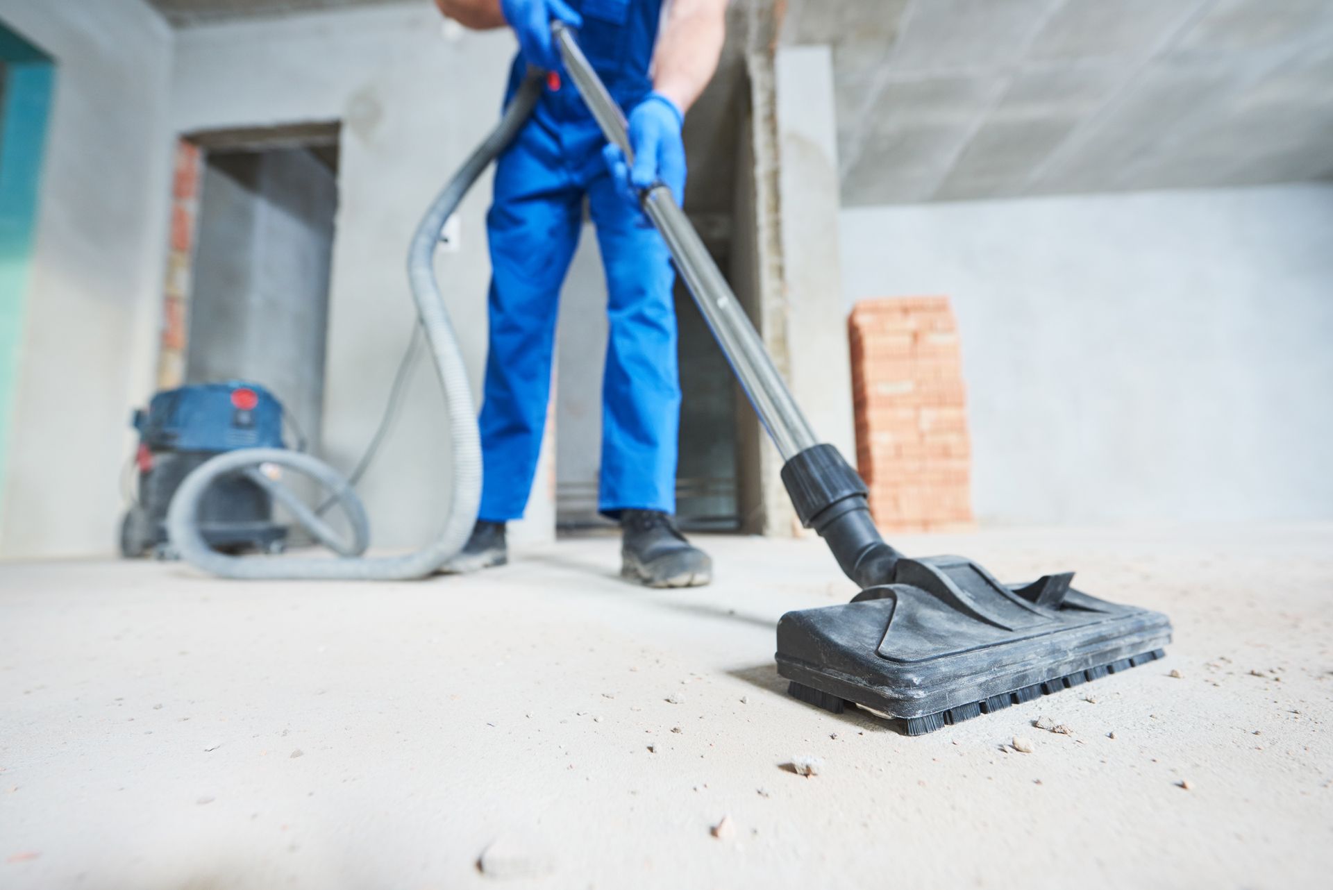 A man is cleaning the floor with a vacuum cleaner