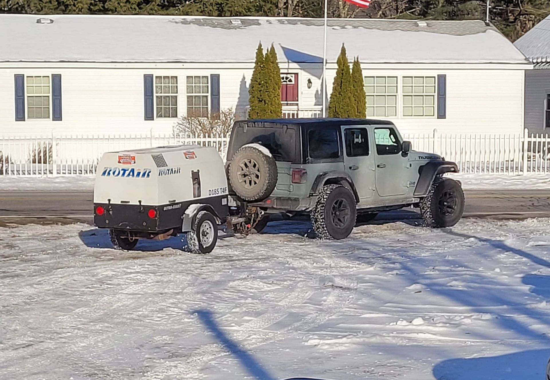 A jeep with a trailer attached to it is parked in the snow