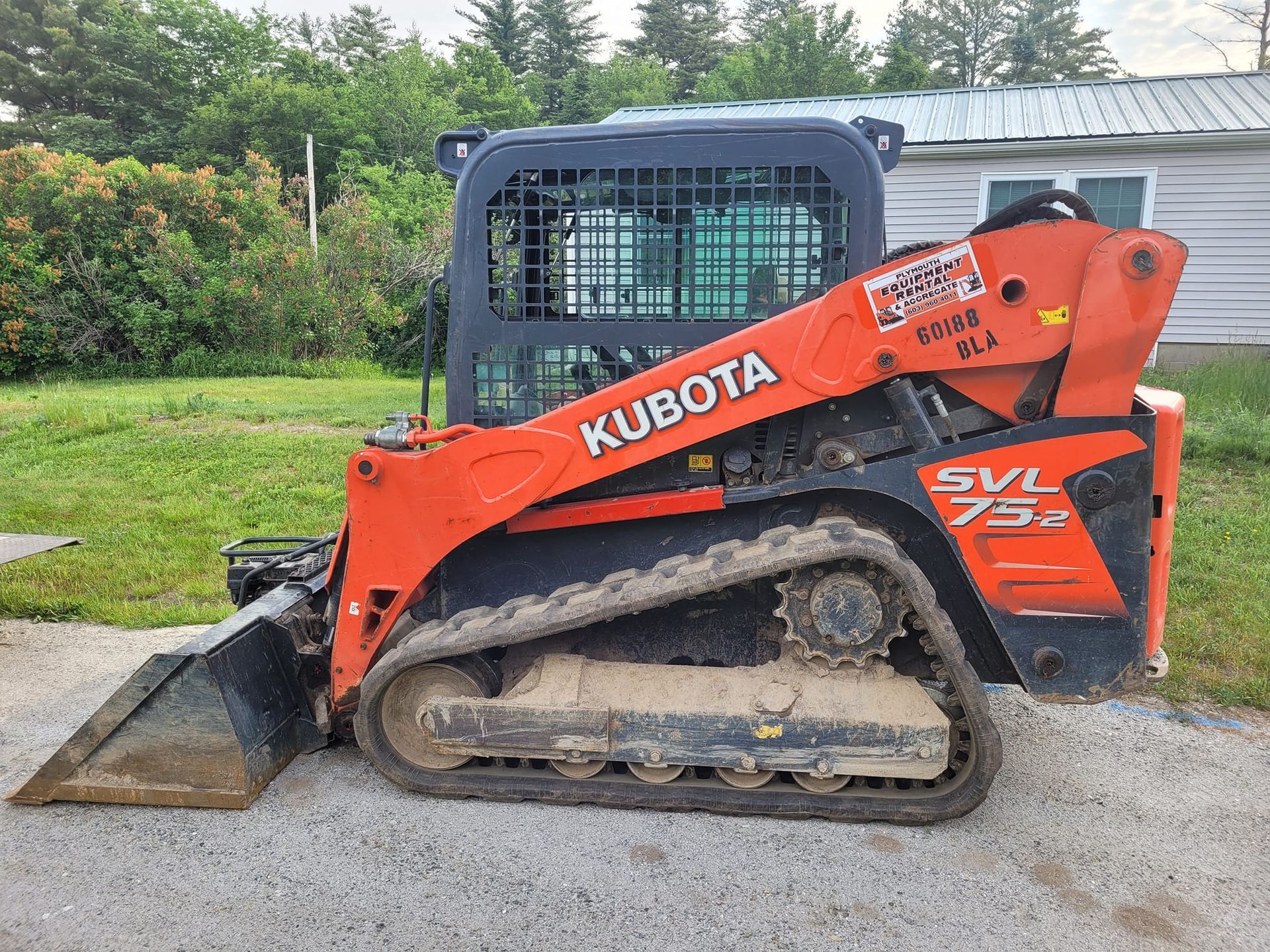 A kubota skid steer is parked in front of a house.