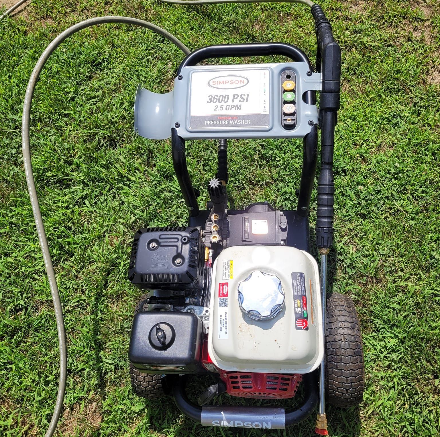 A gas powered pressure washer is sitting in the grass