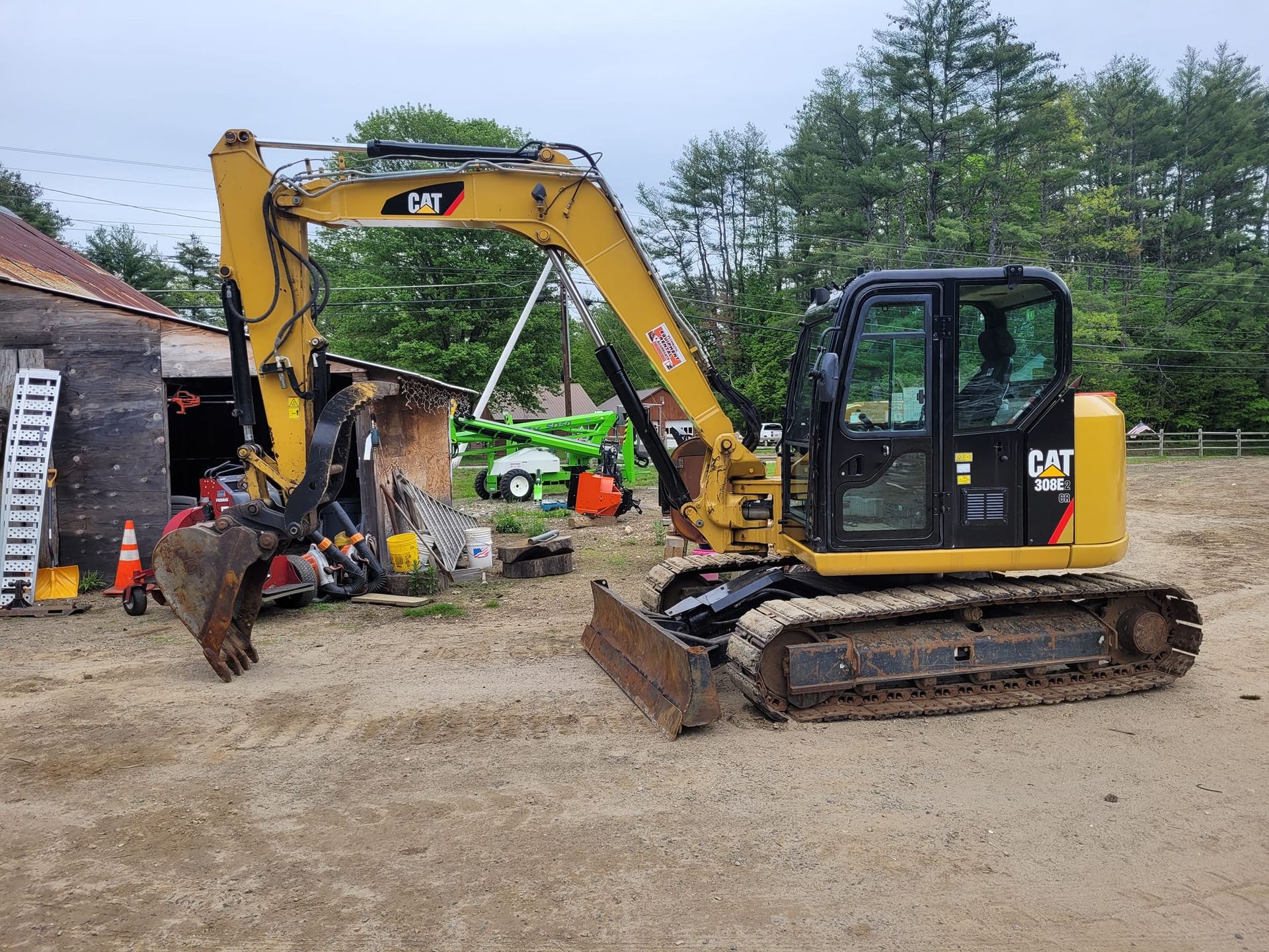 A small yellow excavator is parked in a dirt lot.