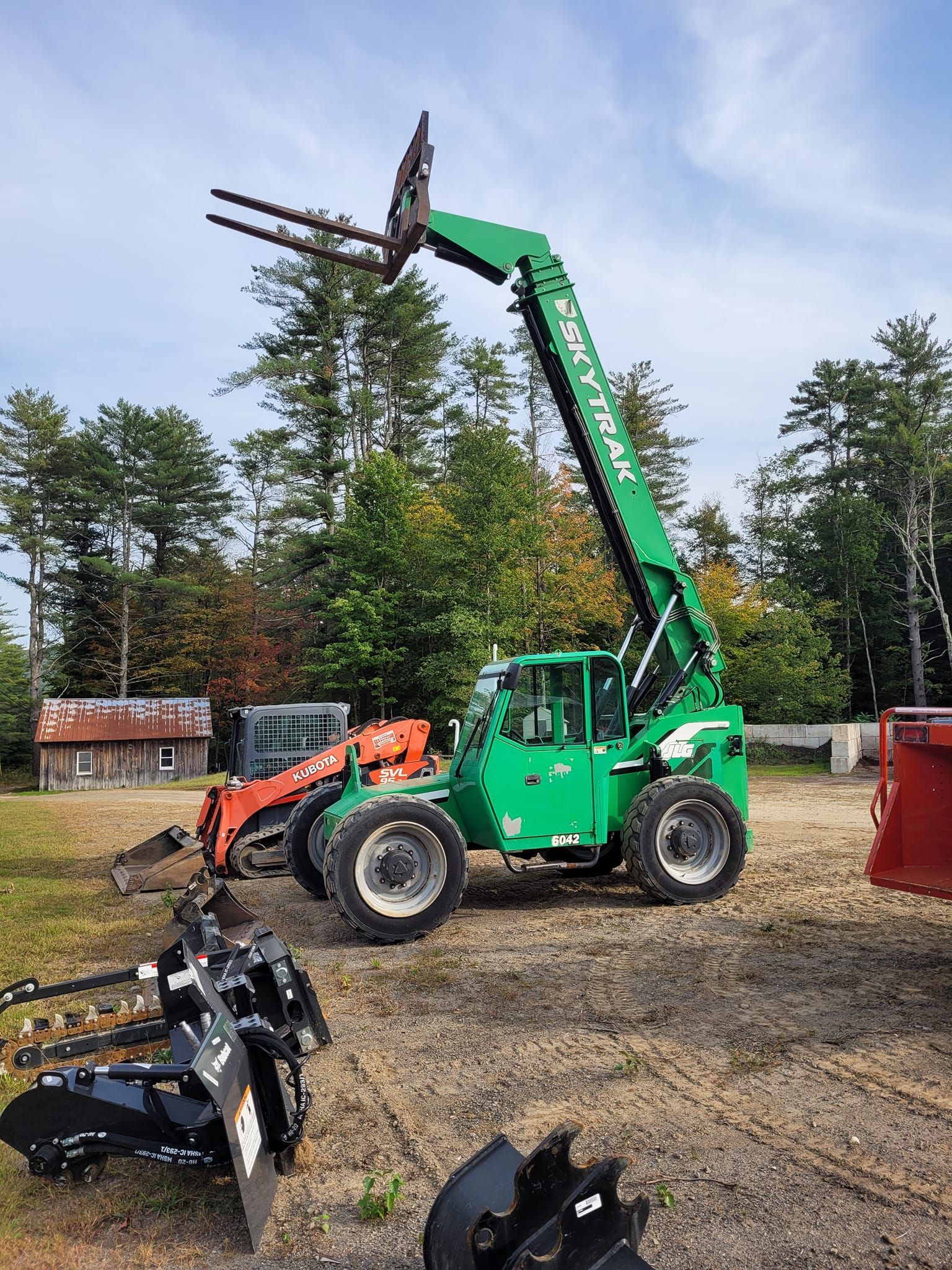 A green forklift is parked in a dirt lot.