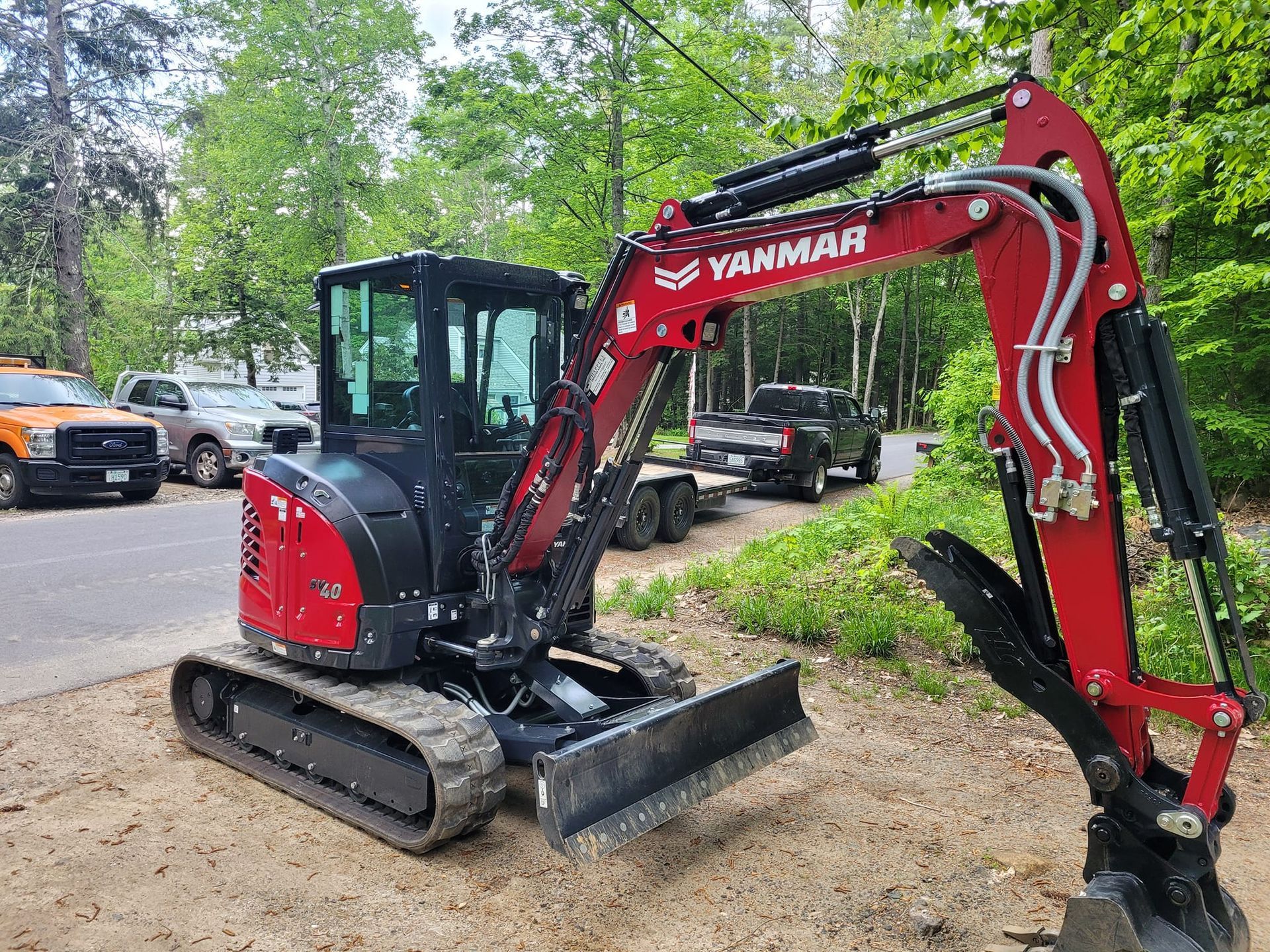 A red and black excavator is parked on the side of the road.