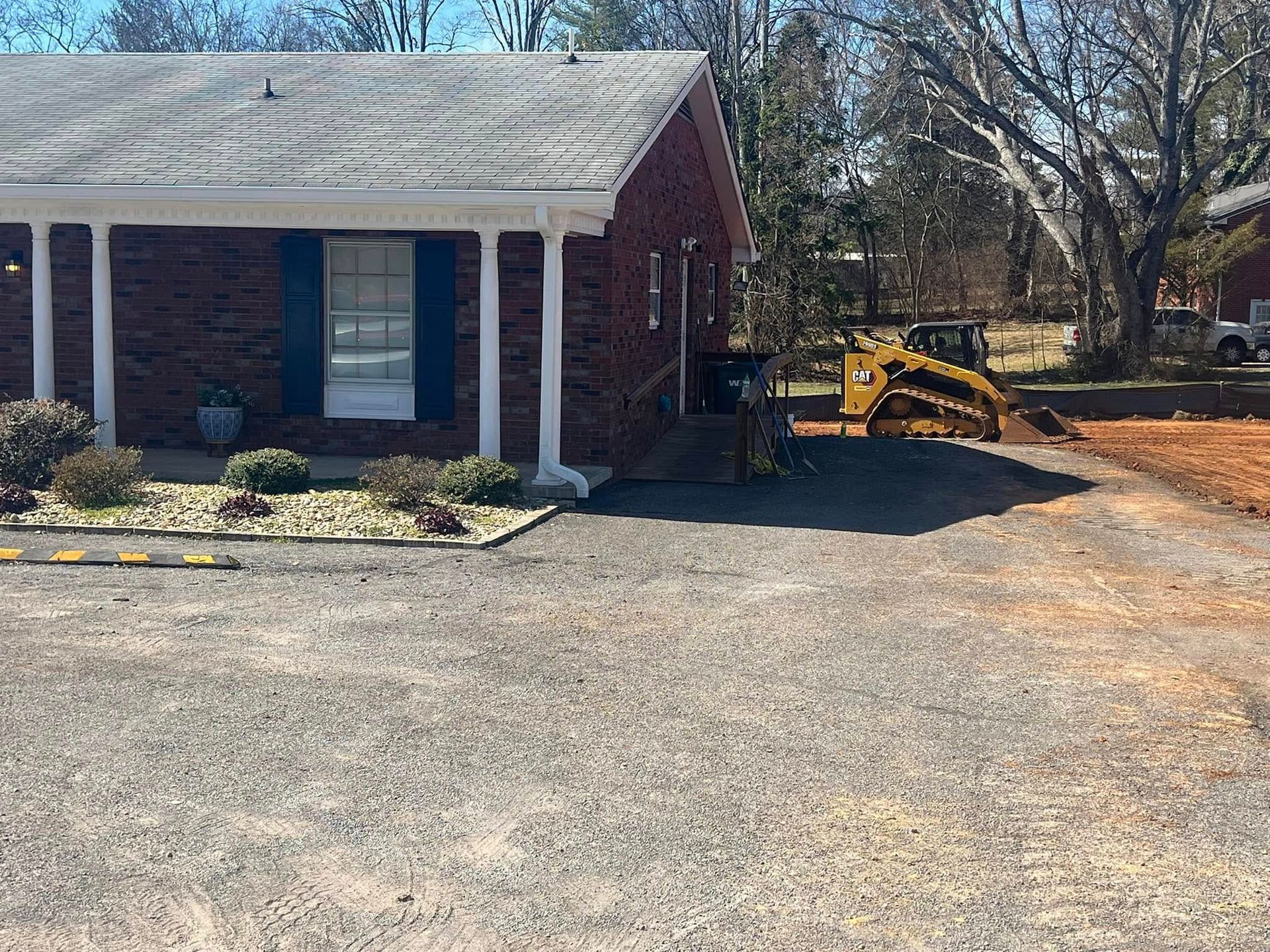 Building with a small bulldozer, driveway being worked on.