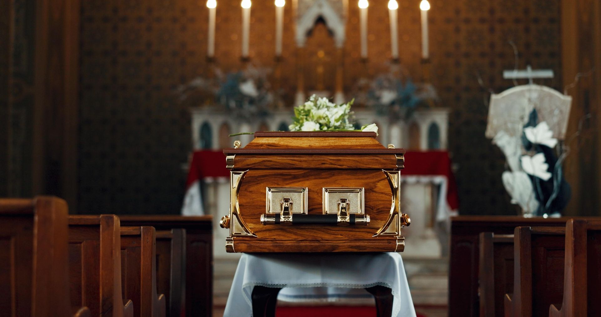 A man in a suit is sitting at a coffin at a funeral.