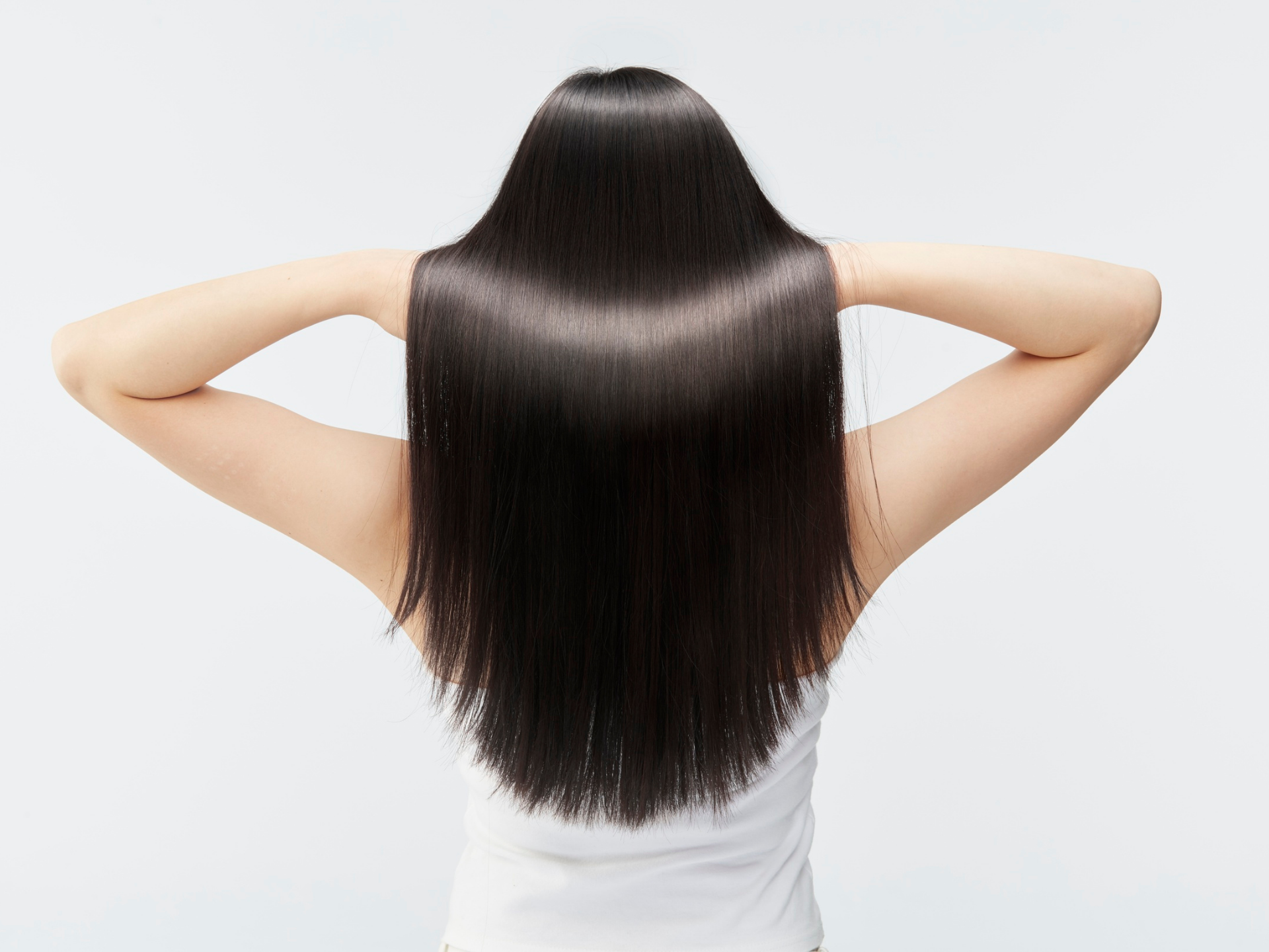 Woman with sleek, straight black hair, arms raised, facing away.