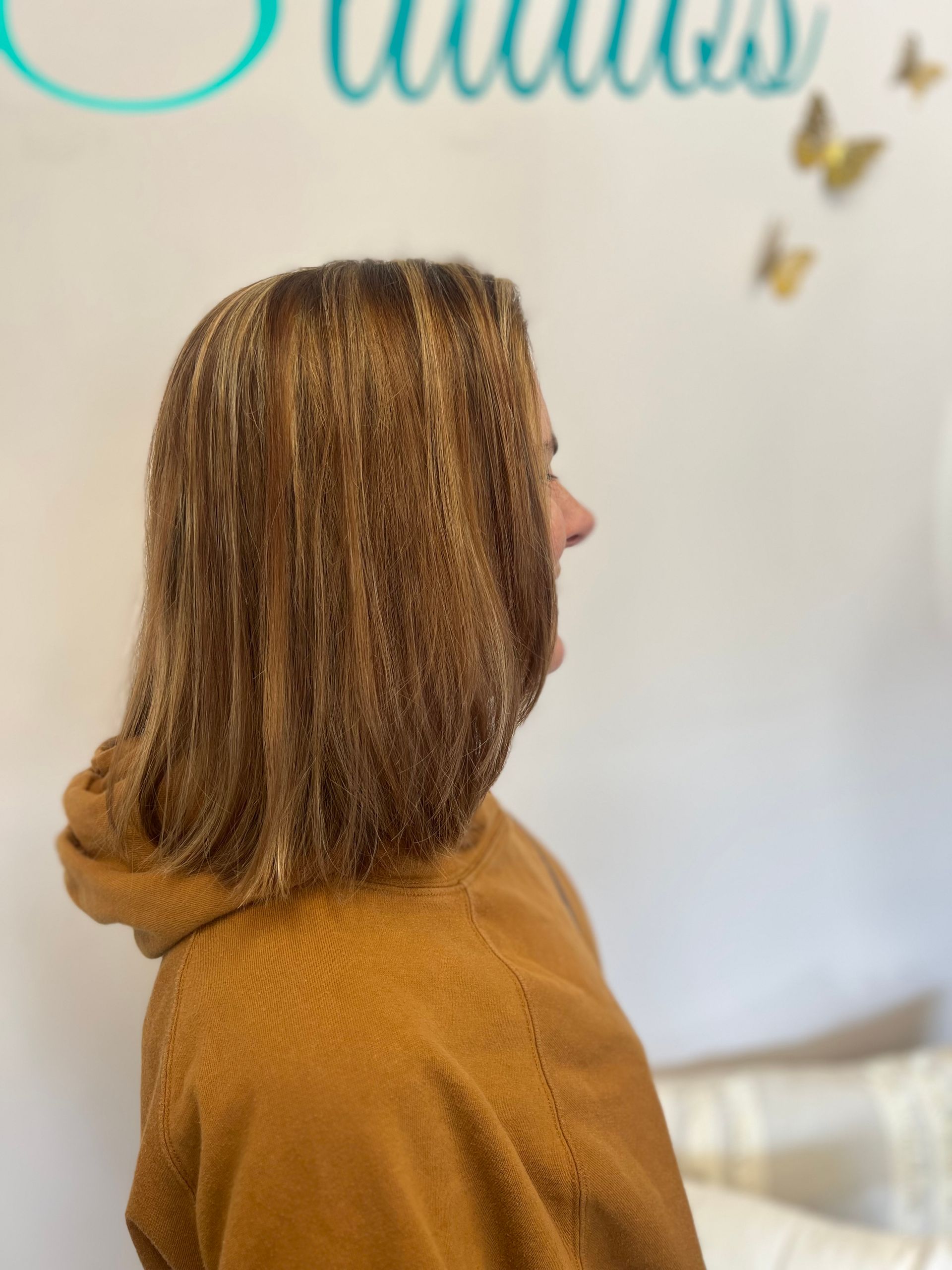 Bride in white dress showing ring to bridesmaids in pink dresses, outdoors.