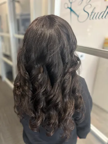 Dark brown, curly hair styled at a salon.