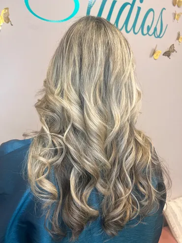 Woman's long, wavy hair, blonde and brown highlights, styled at a salon.