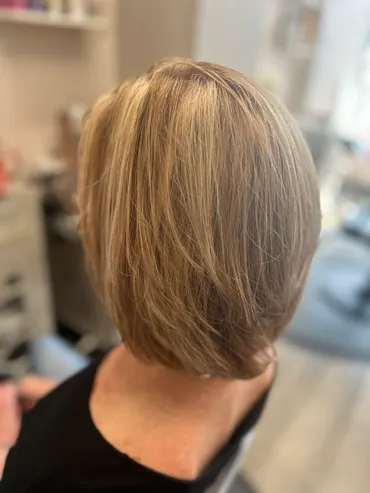 Blonde layered bob haircut, viewed from the back in a salon setting.