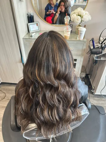 Woman's wavy brown hair with highlights styled in a salon.