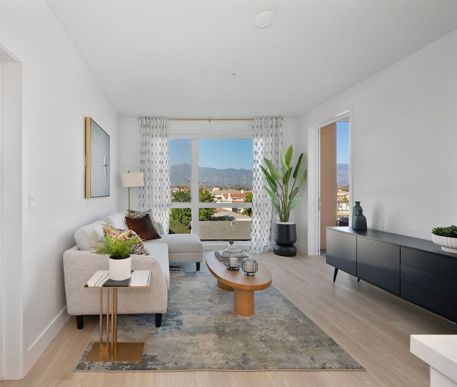 Bright living room with white walls, light wood floor, and large window with a mountain view.