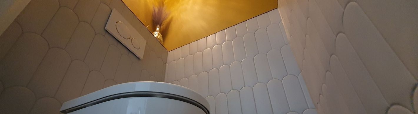 Een close-up van een toilet in een badkamer met witte tegels.