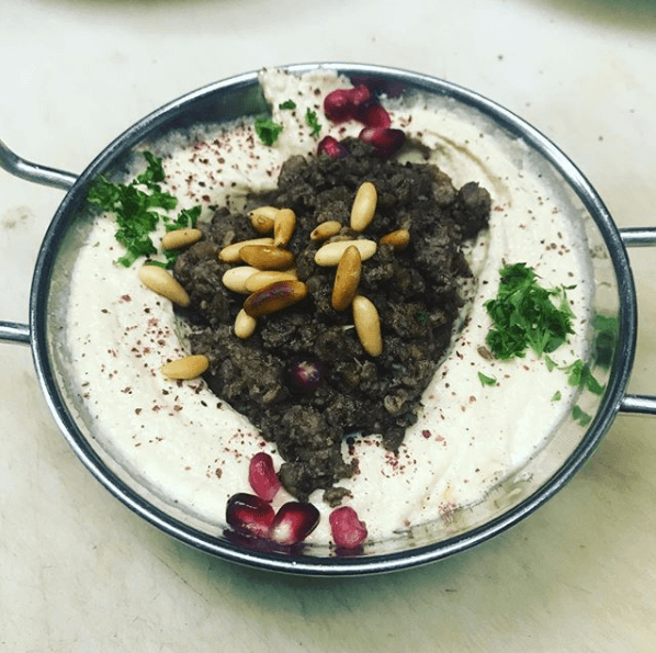 a bowl of food with meat and pine nuts on top