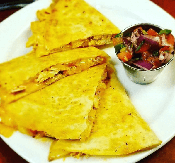 a plate of quesadillas next to a bowl of salsa