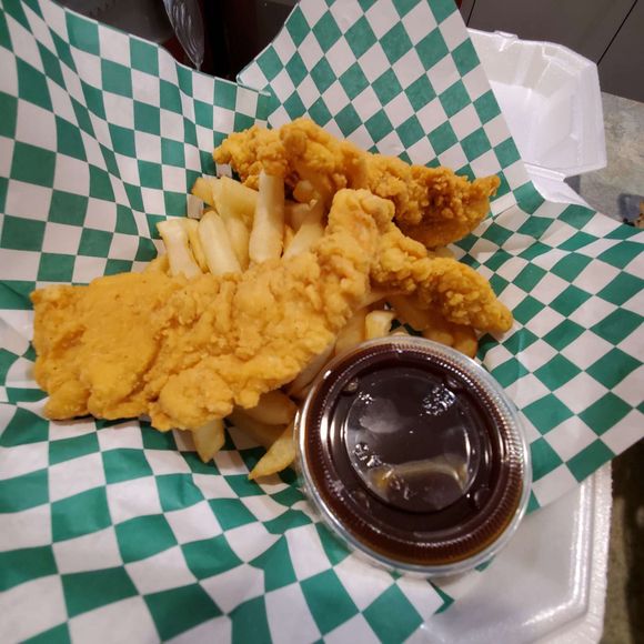 a plate of chicken tenders and french fries with a dipping sauce