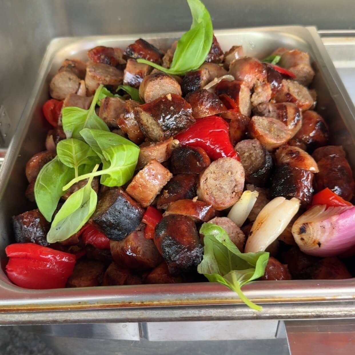 A tray filled with sausages peppers and onions.