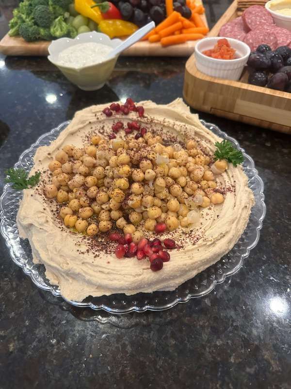A plate of hummus with chickpeas and pomegranate seeds.