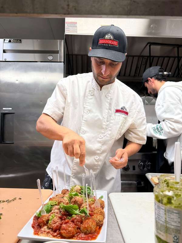 A chef is preparing a plate of meatballs in a kitchen.