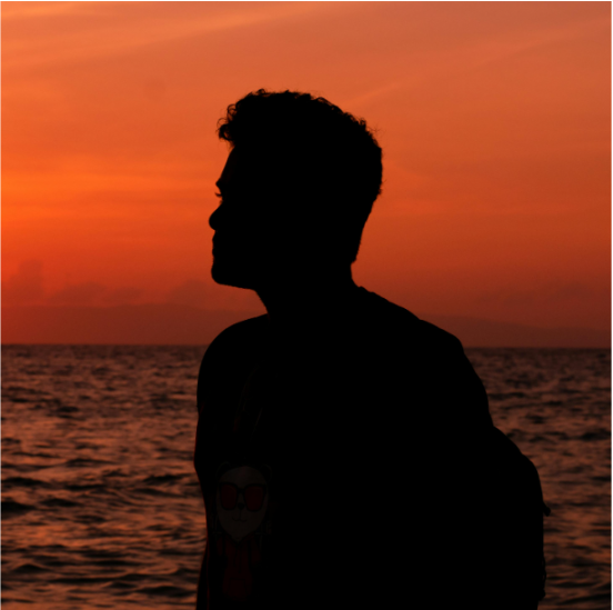 A silhouette of a man standing in front of the ocean at sunset