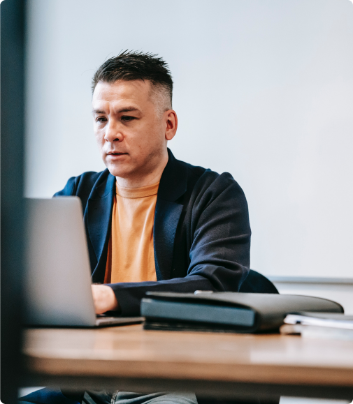 A man is sitting at a table using a laptop computer.