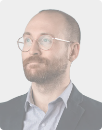 A man with glasses and a beard is wearing a suit