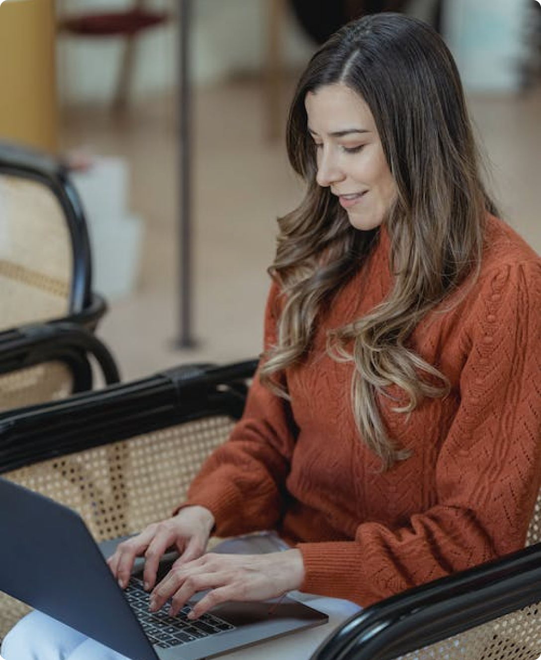 A woman is sitting in a chair using a laptop computer.