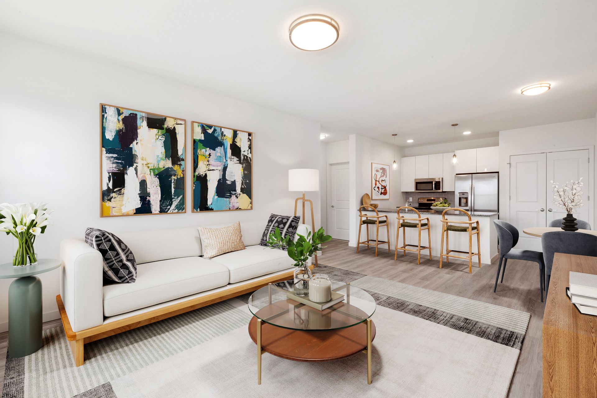 a living room with a couch , coffee table , and paintings on the wall .