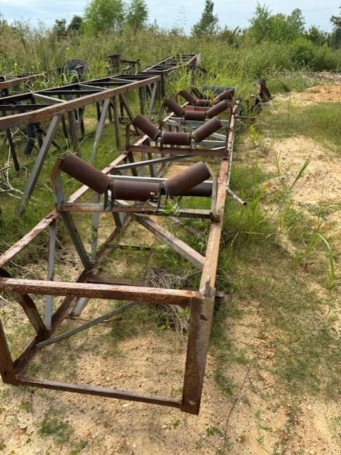 A row of conveyor belts are sitting in a field.