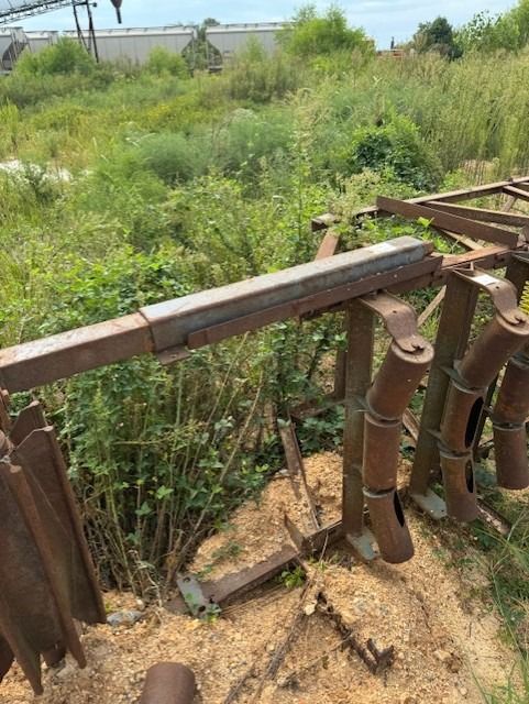 A rusty metal structure is sitting in the middle of a field.