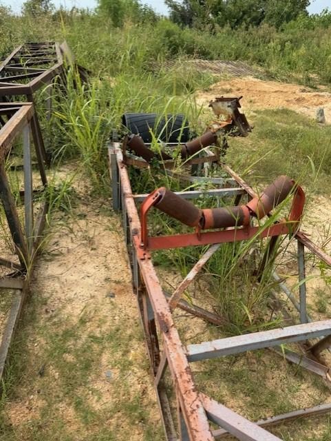 A bunch of rusty metal pieces are sitting on top of a dirt field.