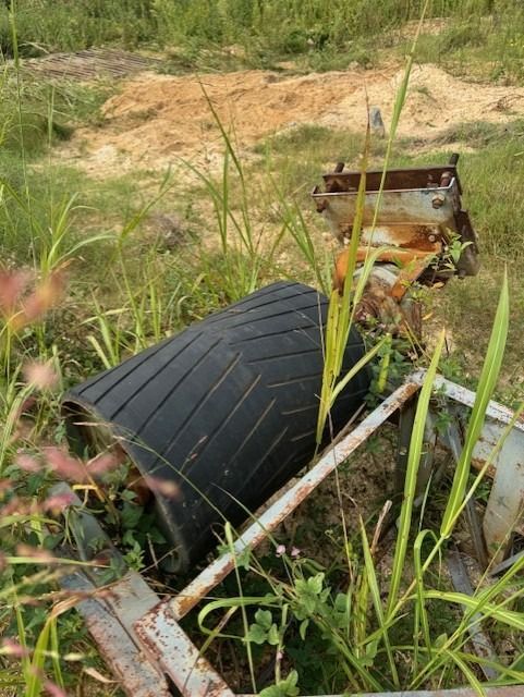A black object is laying in the grass in a field.