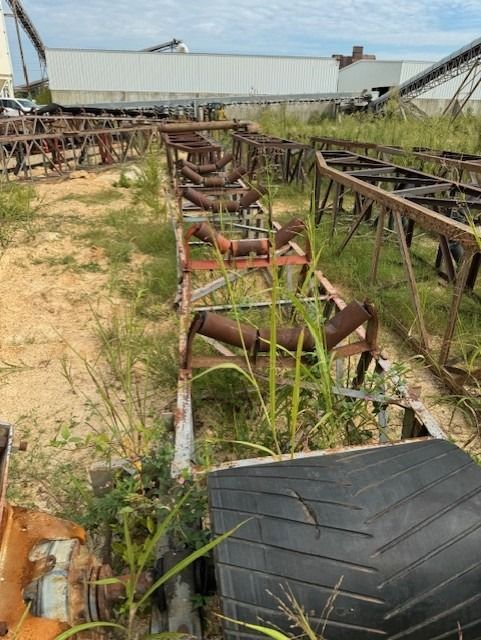 A row of conveyor belts are sitting in a field.