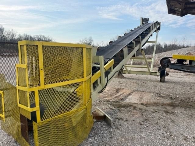 A conveyor belt is sitting on top of a dirt field.