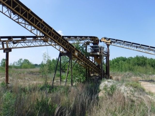 A conveyor belt in a field with trees in the background