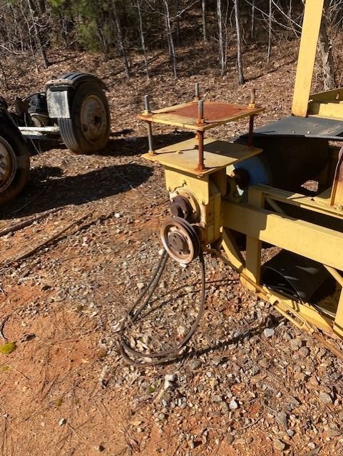 A yellow tractor is parked on a dirt road