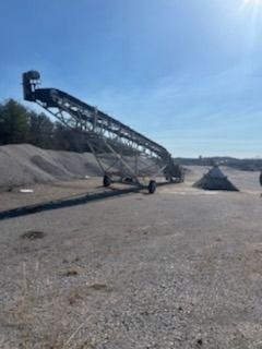 A conveyor belt is sitting in the middle of a dirt field.