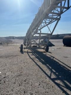A conveyor belt is sitting on top of a gravel road.