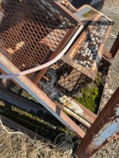 A rusty metal fence is sitting on top of a pile of dirt.
