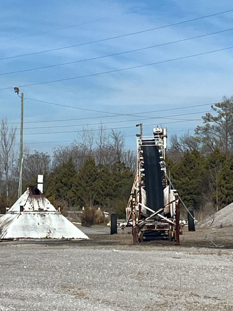 A conveyor belt is sitting in the middle of a dirt field.