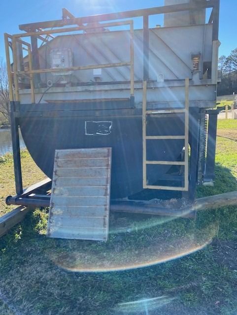 A small house is sitting in the grass next to a body of water.